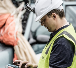 Man in a high visibility vest and hard hat using a tablet